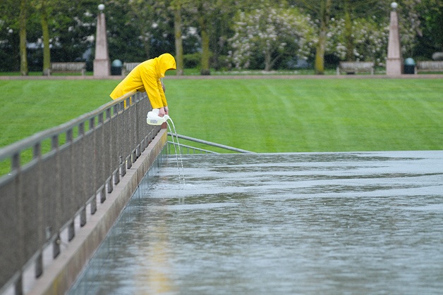 A City of Bellevue parks employee adds chemicals to adjust the pH balance of the water in the fountain at Downtown Park in Bellevue during a rain shower on Tuesday