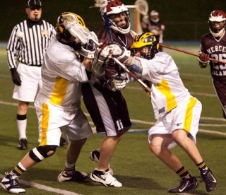 Islanders lacrosse player Colton Knebel is sandwiched by two Bellevue players in Mercer Island's 14-7 win over the Wolverines Wednesday night in Bellevue.