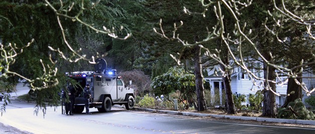 Police wait outside the home where a man has barricaded himself inside