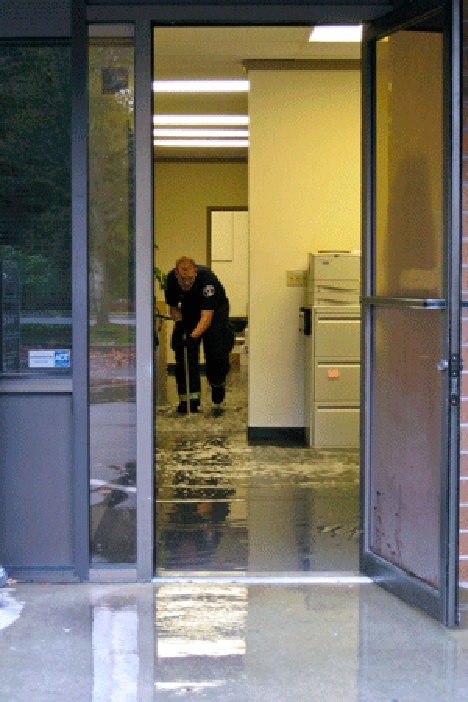 A Bellevue firefighter pushes water out of the Bellevue Reporter offices on Wednesday morning. A broken pipe forced the newsroom to move its operations to Mercer Island Reporter.