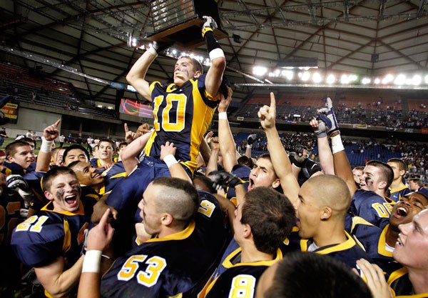 Taylor Anderson hosts the state championship trophy as he celebrates with his Bellevue High School teammates on Saturday