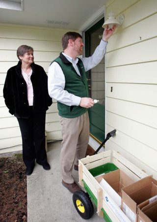 Puget Sound Energy manager Andy Swayne changes an incandescent porch light to a CFL bulb as Mindy Garner
