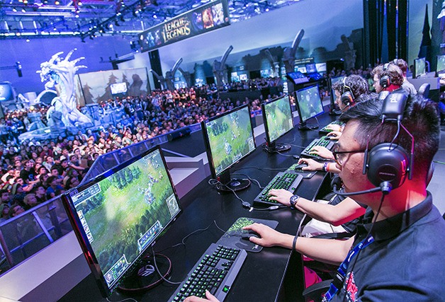 Participants play a PC game in front of an audience at Gamescom 2014.