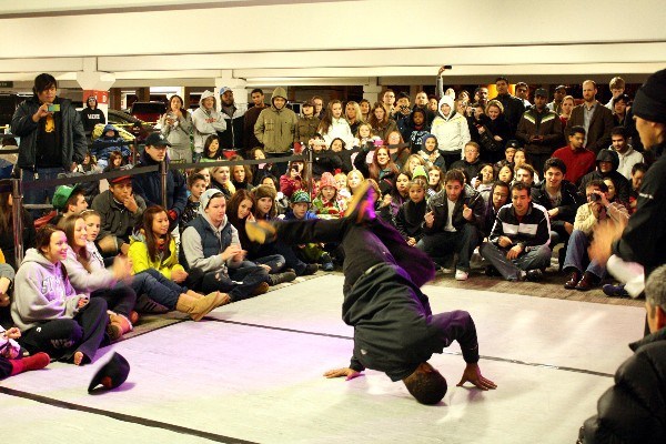 A breakdancer from the group Massive Monkees entertains a crowd waiting in a parking garage at Bellevue Square for a chance to get free tickets to a Miley Cyrus concert sponsored by Microsoft. The concert is part of Microsoft's opening of a retail store at the Square.