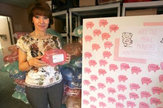 World Impact Network's Executive Director Gabriella Van Breda holds one of the piggy banks that are used to collect money to raise $50