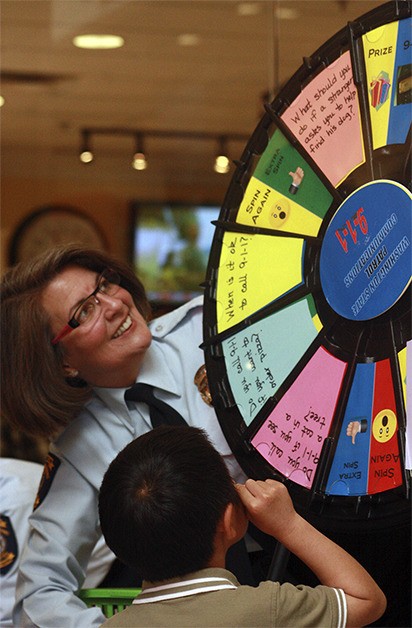 An officer mans the 9-1-1 prize wheel during Saturday's Child Safety and Law Enforcement Appreciation Day at the Factoria Mall. Children received prizes for answer questions on the wheel.