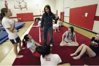Newport gymnastics coach Farrah Griffin talks to her team as the Knights prepare to shift to the 4A class - and face new competition.