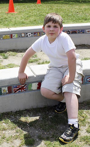 Nick Ushka sits with the tile he designed as part of Sherwood Forest Elementary's new art installation. The tiles were unveiled to the community on Thursday