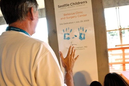 Children's Hospital CEO Dr. Thomas Hansen observes from a distance as a small group of kids leave their lasting handprints on the dedication wall at the new facility site in Bellevue.