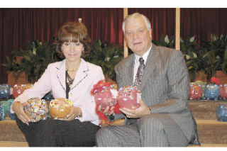 Gabriella Van Breda of World Impact Network and Westminister Chapel Senior Pastor Gary Gulbranson hold some of the decorated piggy banks that church members used to collect funds to feed the needy.