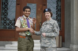 Rahul Brito shakes hands with State Inspector General Col. Debra Lewis of the Washington National Guard after receiving an Operation Iraqi Freedom coin for his efforts collecting school supplies for children in Iraq. Brito has earned a host of honors this year for his service and academic accomplishments.
