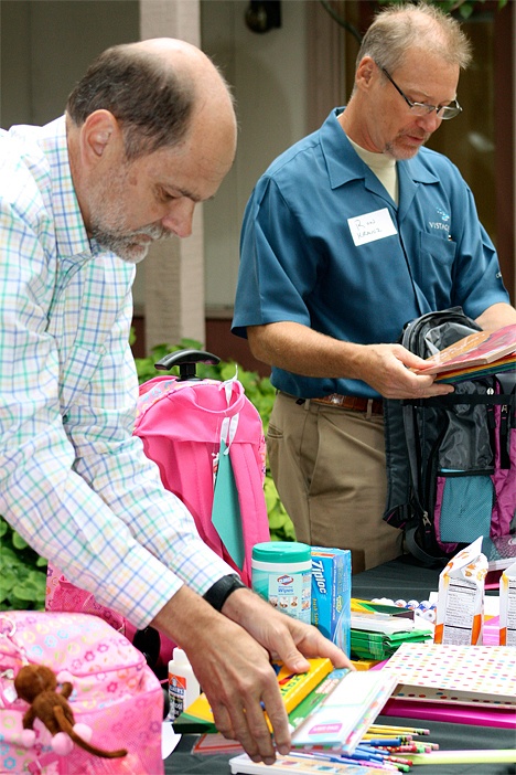 BizEnrich members Art Olsen (left) and Ron Kranz sort through a collection of school supplies to put into school backpacks for foster kids.