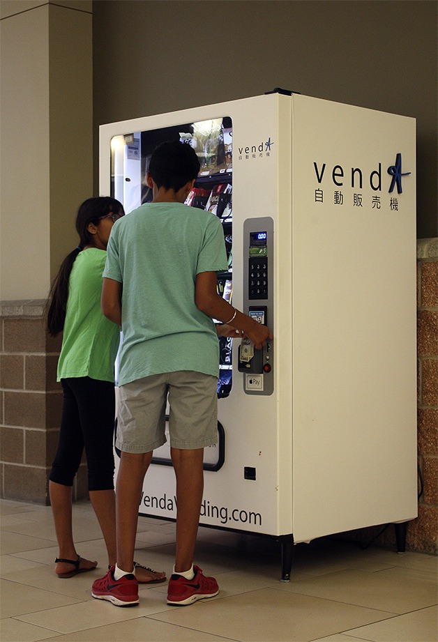 Two children purchase snacks from the Venda Vending machine in the Marketplace at Factoria.