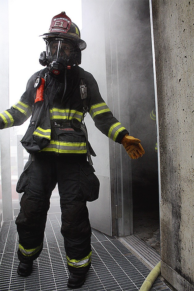 Bellevue firefighter Maia Earle emerges from a smoking building used for training during the Fire Ops 101 training on Monday
