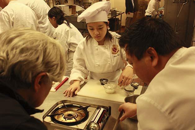 Newport instructor Tracy Green and The Golf Club at Newcastle Executive Chef Jesse Olsen help Fiona Lee change out the butane cylinder on a burner during a recent culinary arts team practice.