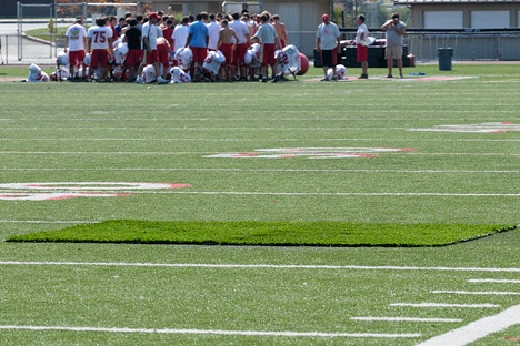 A piece of field turf covers the fire damage from a Tuesday night arson on the football field at Newport High School in Bellevue during practice on Friday.