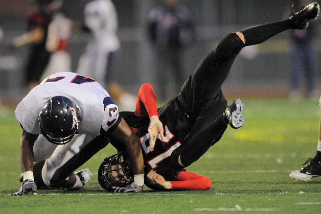 Totem QB Andrew Engles (12) is hit by Rebel LB Sitiveni Tamaivena (43) while trying to recover a fumbled snap at Sammamish on Friday