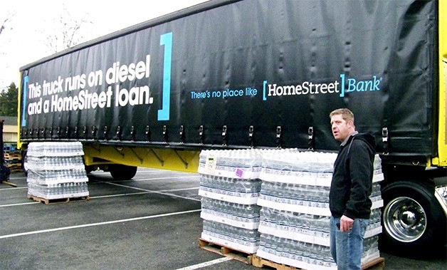 Band of Brothers Northwest founder Chris Black stands next to pallets of water donated by Talking Rain during Friday's event for Typhoon Haiyan aid relief to the Phillipines at the Crossroads Bartell Drugs