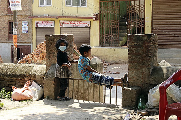 Nepalese children relax near rubble on May 9. Around 8