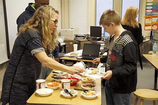 Piper Sangston scoops out frosting for one of her students during a candy house making assignment at Tillicum Middle School. Sangston recently won the Distinguished School Social Worker of the Year award from the Washington Association of School Social Workers.