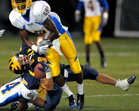 Wolverine RB Sean Coley (4) is tackled by Grant defenders at Memorial Stadium in Seattle on Saturday. Bellevue was shutout 14-0 by the visiting team from California.