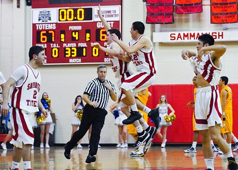 Totem sophomores George Valle (32) and John Steinberg leap in celebration after holding on for 67-64 win over Bainbridge in opening round of 3A district tournament play at Sammamish on Tuesday.