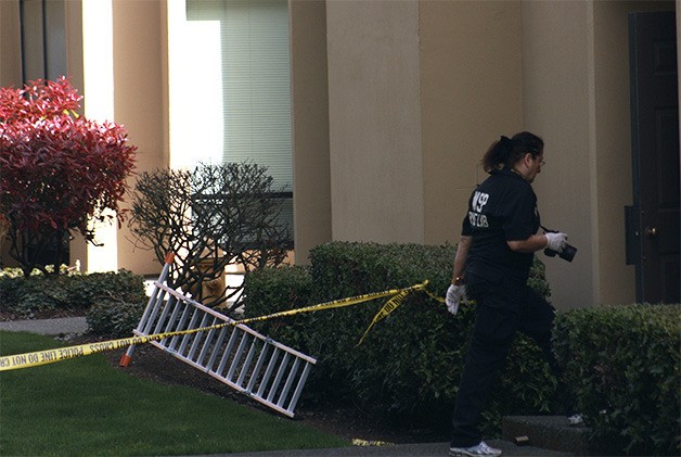 An officer with the Washington State Patrol Crime Lab assisting with a murder investigation enters an apartment complex at the Twelve Central Square apartments on Northeast 12th Street in Bellevue on Monday