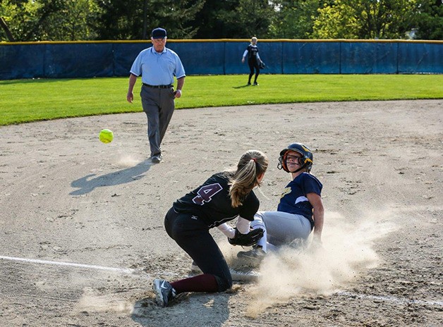 A Bellevue player slides safely into third base after the ball gets away from Mercer Island third baseman Olivia Kane on April 17 at Bellevue High School. The Wolverines improved their KingCo record to 3-6 overall.