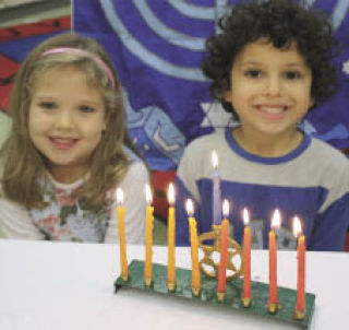 Pre-kindergarten students Miranda Brown and Dan Firstenberg light the preschool menorah at the Jewish Day School in Bellevue.