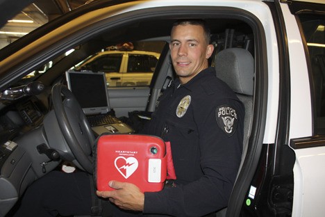 Bellevue Police officer Seth Tyler with an automatic external defibrillator (AED). All Bellevue patrol officers will now have the device in their squad cars.