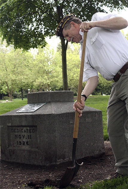 Bellevue veteran Bob Shay turns over dirt surrounding the 'Lest We Forget' memorial in Downtown Park on Monday