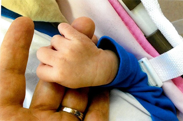 An infant holds Kelye Kneeland’s finger during her stay at the House of Grace orphanage in China. The orphanage’s owner