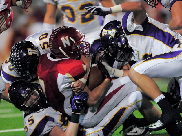 Issaquah defenders Duncan Hamilton (55) and Austin Richert (50) tackle Knights RB James Dupar (9) during a game at Newport High School on Friday.