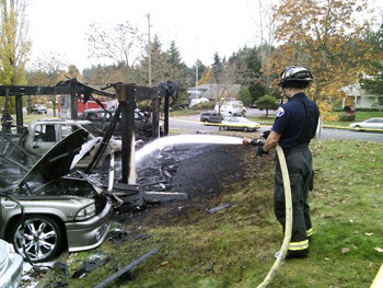 Firefighters work to put out a fire at a Bellevue apartment complex Friday morning that destroyed five cars and damaged several more.