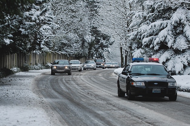 Bellevue Police car escorts vehicles after 148th Avenue SE was reopened after sanding in Lake HIlls neighborhood of Bellevue on Thursday morning.