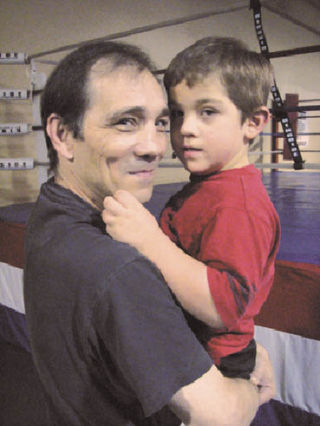 Greg Haugen holds his grandson Blaine Smith in front of the boxing ring where the 48-year-old Auburn man trains boxing prospects. Haugen is using his notoriety as a former world champion boxer to fight autism