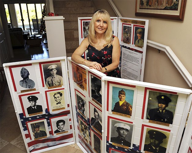 Janna Hoehn stands by photos of some of the Vietnam veterans she has found to connect to the Vietnam Veterans Memorial Wall.