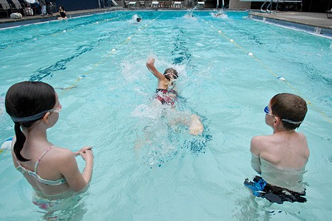 Members of the swim teams at Bellevue’s Triangle Pool get in the water for the first time this year as practice for swimming season officially opened on Monday