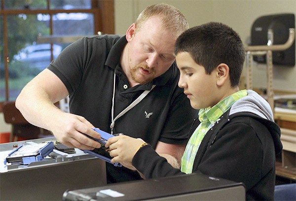 A student at Highland Middle School examines various computer parts with one of Jubilee Reach's site coaches during the club's new Science