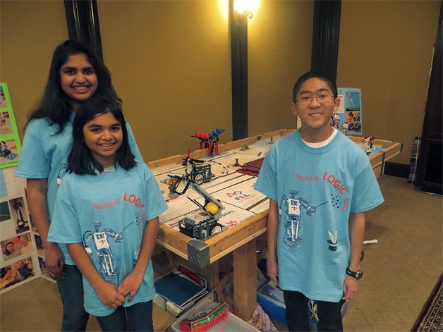 (Left to right) Alisha and Eshika Saxena and Tyler Okamoto stand near a competition-sized table the Saxena family buit for the group to practice.
