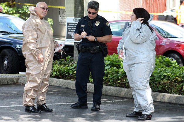 Two office workers were placed in hazardous materials protective suits by Bellevue firefighters to contain any possible exposure at the 520 112th Avenue NE office building in Bellevue on Monday.
