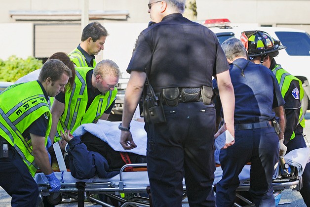 A pedestrian struck by a car is moved on a backboard by Bellevue firefighters at the intersection of 120th Avenue NE and Bel-Red Road in Bellevue on Monday morning.