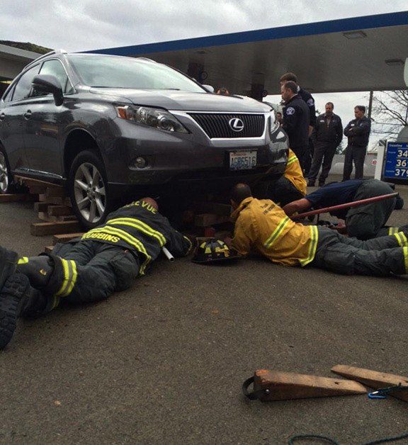 Bellevue firefighters remove a Chevron gas station employee from under an SUV on  Wednesday
