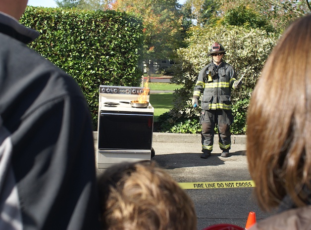 Bellevue firefighter Will Dunne demonstrates the dangers of a fire on a stove to onlookers at Fire Station No. 3 in Crossroads on Saturday morning