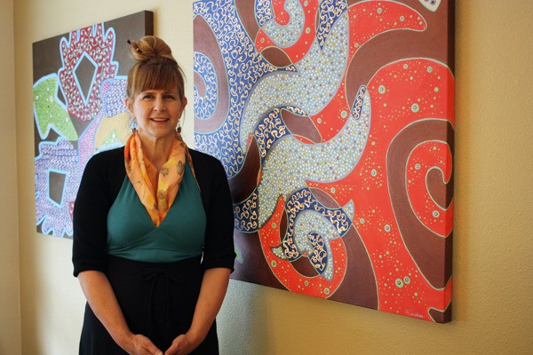 Mercer Island artist Louise Hankes poses in front of two paintings from her 'Whirlism' series.