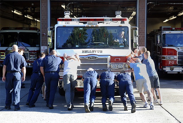 Firefighters and department mechanics push the new $1.2 million ladder truck into its bay in Fire Station 3.