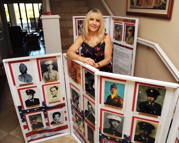 Janna Hoehn stands by photos of some of the Vietnam veterans she has found to connect to the Vietnam Veterans Memorial Wall.