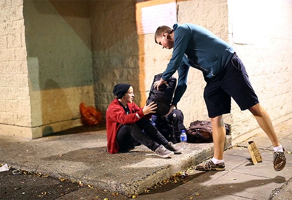 One of Sleepless in Seattle's volunteers hands out a sleeping bag to a homeless man in Seattle. The group is trying to raise $75