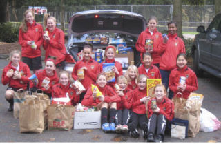Members of Kristi Sahlinger’s Newport GU-13 Red soccer team pose with some of the food the team collected during a recent food drive for Hopelink.