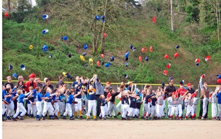 Members of Bellevue West Little League toss their caps into the air following the opening day ceremony.